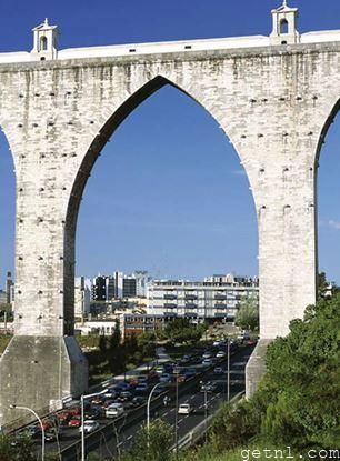 The elegant arch of the Águas Livres Aqueduct looming over Lisbon’s traffic